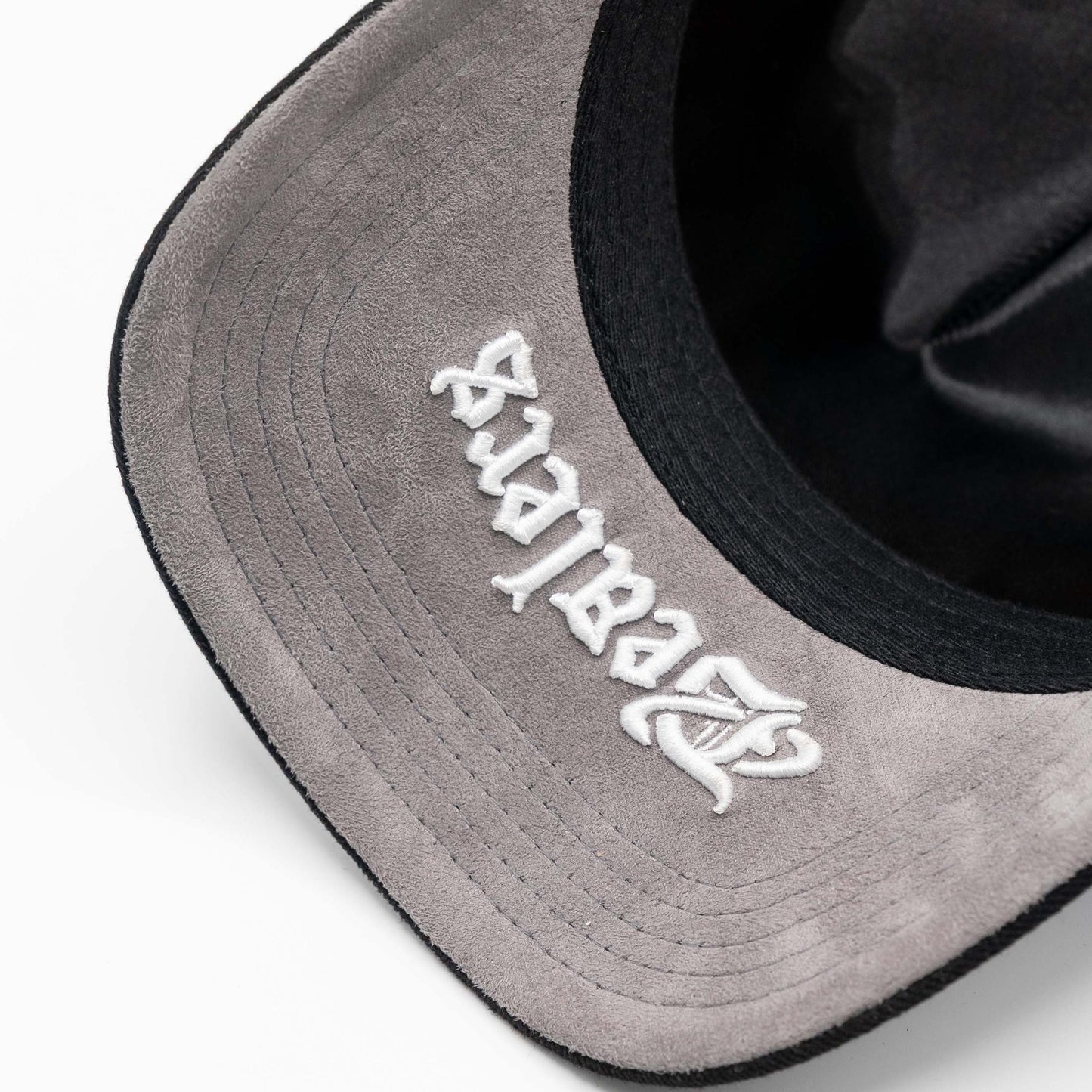 Close-up of suede grey hat brim with white embroidered script, urban streetwear style