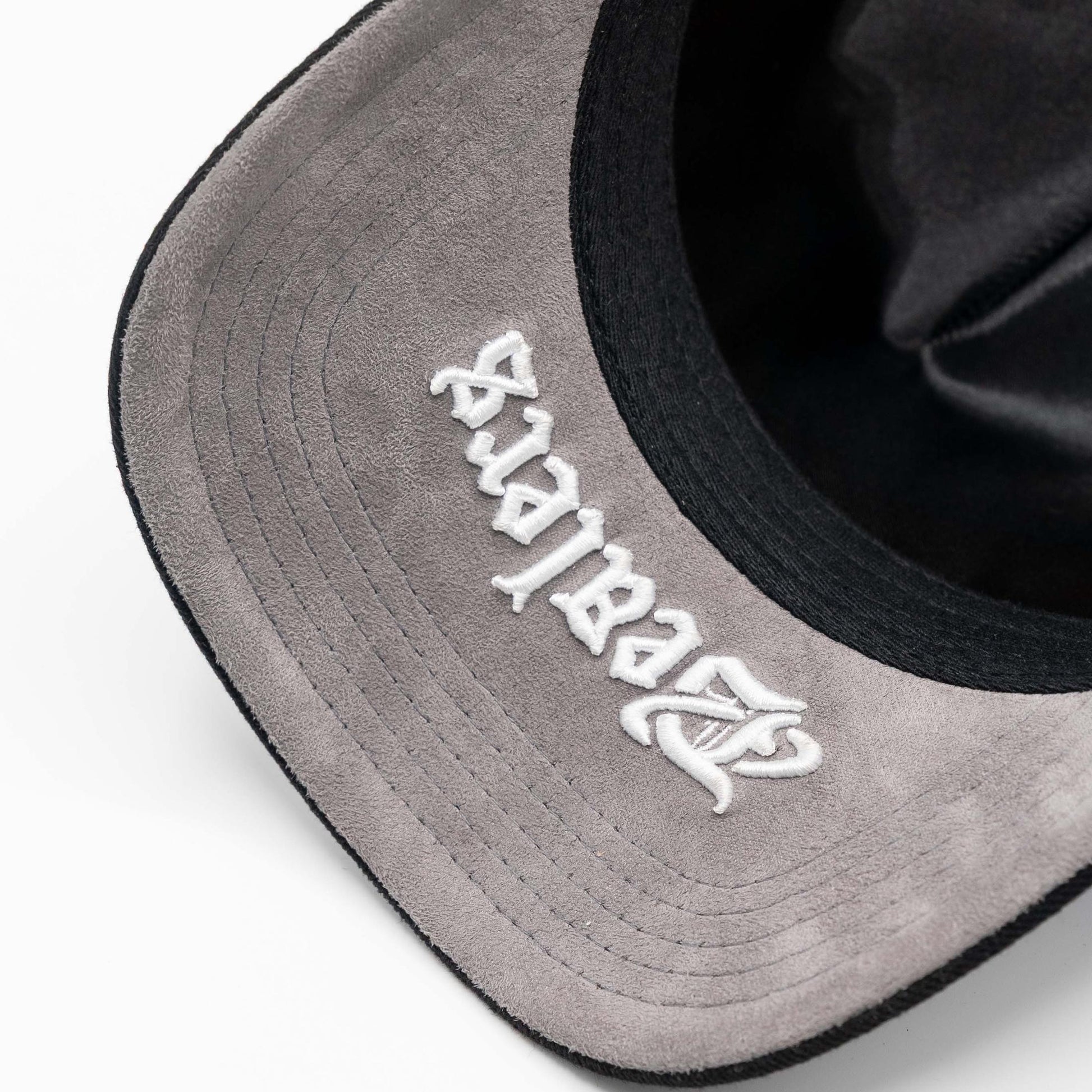 Close-up of suede grey hat brim with white embroidered script, urban streetwear style