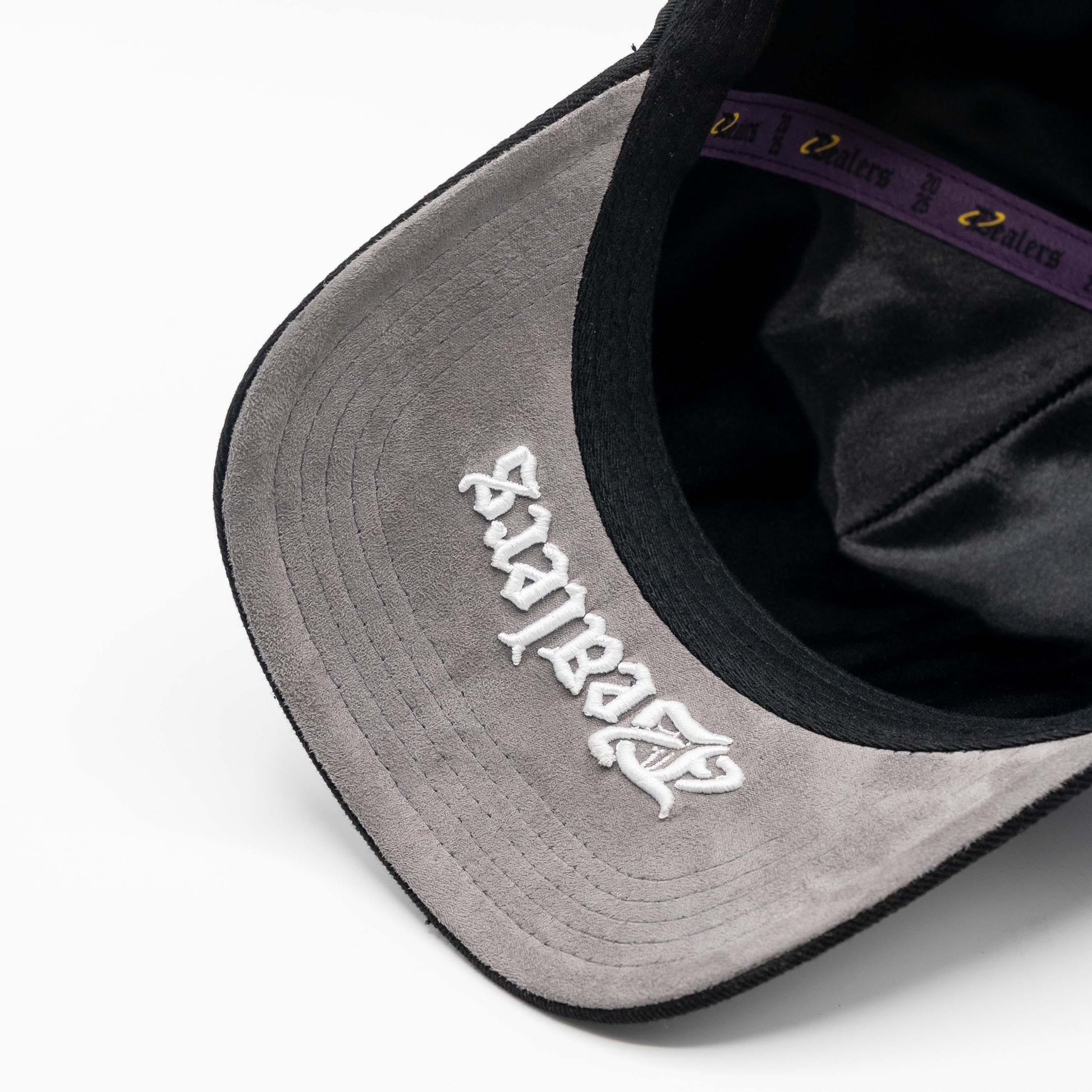 Gray suede brim hat with embroidered white lettering and purple interior band