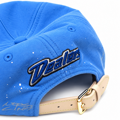 Close-up of the Dealers script on the back and the gold buckle on the tan leather strap