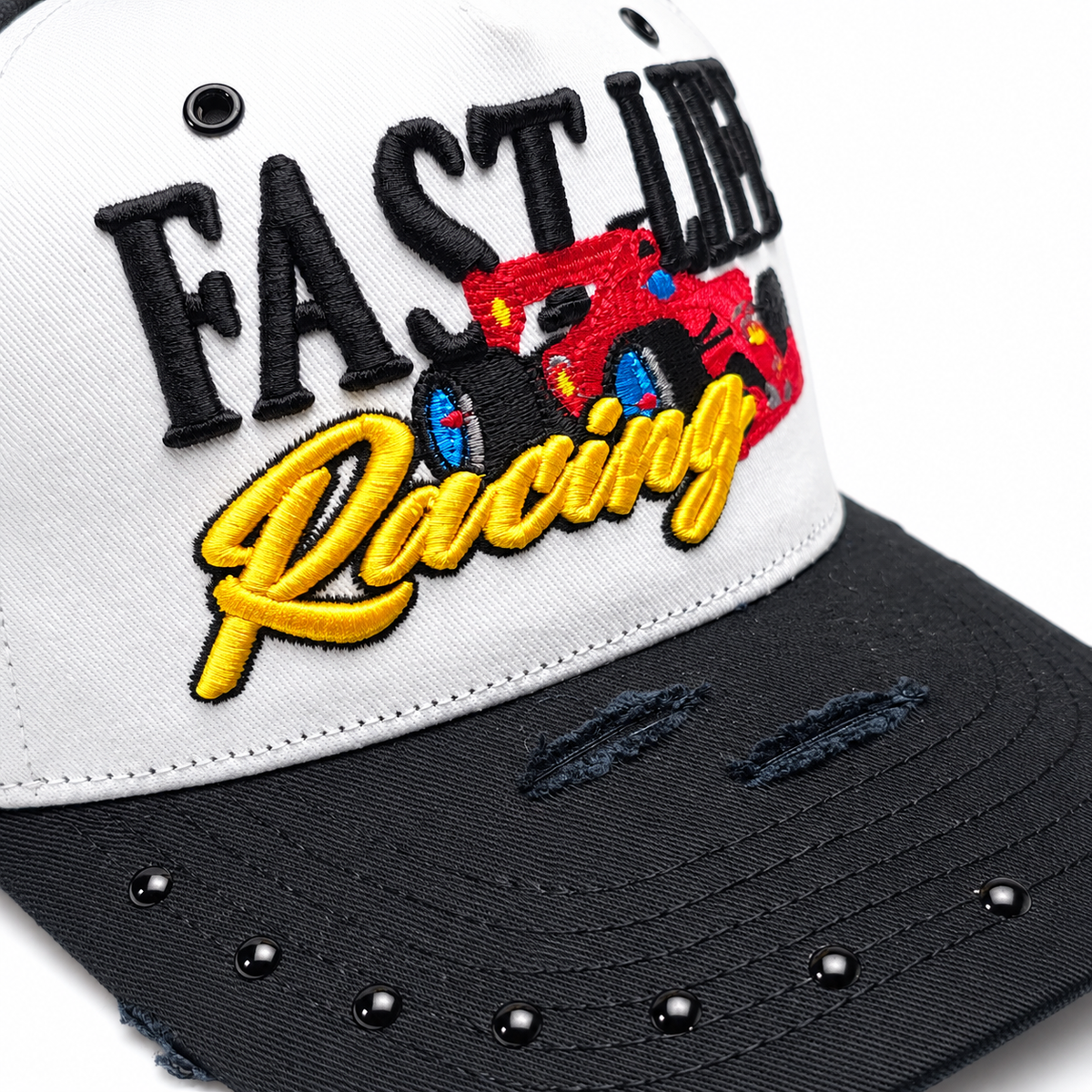 Close-up of the 3D puff FAST LIFE and Racing embroidery, stitched race car and studded distressed brim